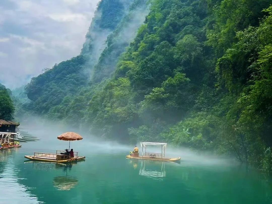 Emerald green river in deep karst gorge, wooden boats and Tujia stilt?houses, lush mountain valley scenery.