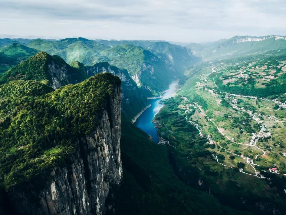 Enshi Grand Canyon in Hubei with towering sandstone peaks, misty clouds, green cliffs, and a scenic cliffside walkway