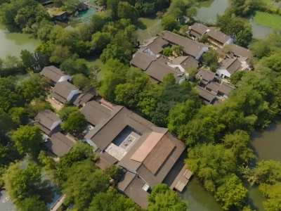 Aerial shot of Xixi Wetland boutique resort, grey-tiled buildings surrounded by water & woods