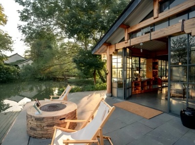 Waterfront courtyard of Xixi Wetland hotel, lounge chairs, fire pit & wetland river view