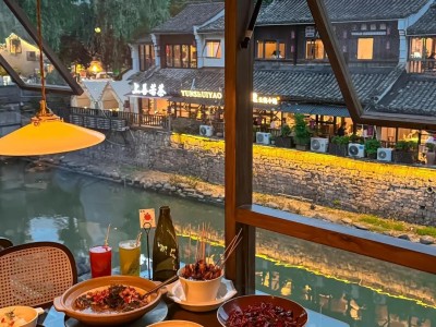 Dining view from riverside restaurant at Xiaohe Straight Street, local food and lit canal old buildings