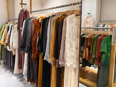 Various silk dresses and garments hanging in the clothing section of a silk shop