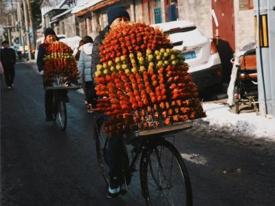 In winter, an elderly man sells candied hawthorns by bicycle in a Beijing hutong
