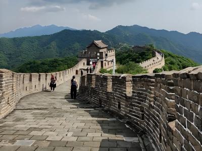 Visitors walking along the Mutianyu Great Wall with watchtower and green mountains Visitors walking along the Mutianyu Great Wall with watchtower and green mountains