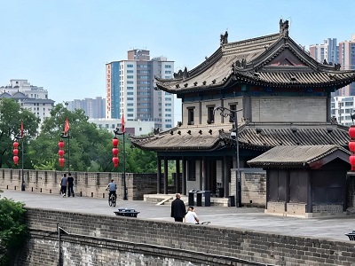Traditional gate tower with ornate roofs and red lanterns along the ancient wall