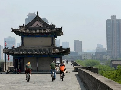 Cyclists riding along Xi'an Ancient City Wall with a historic tower and city skyline. Cyclists riding along Xi'an Ancient City Wall with a historic tower and city skyline.