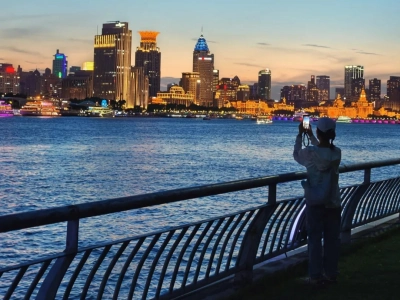 Tourist taking photos of Bund skyline from riverside promenade, Shanghai