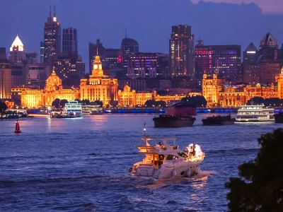 Yacht and cruise boats sailing on Huangpu river against illuminated bund buildings
