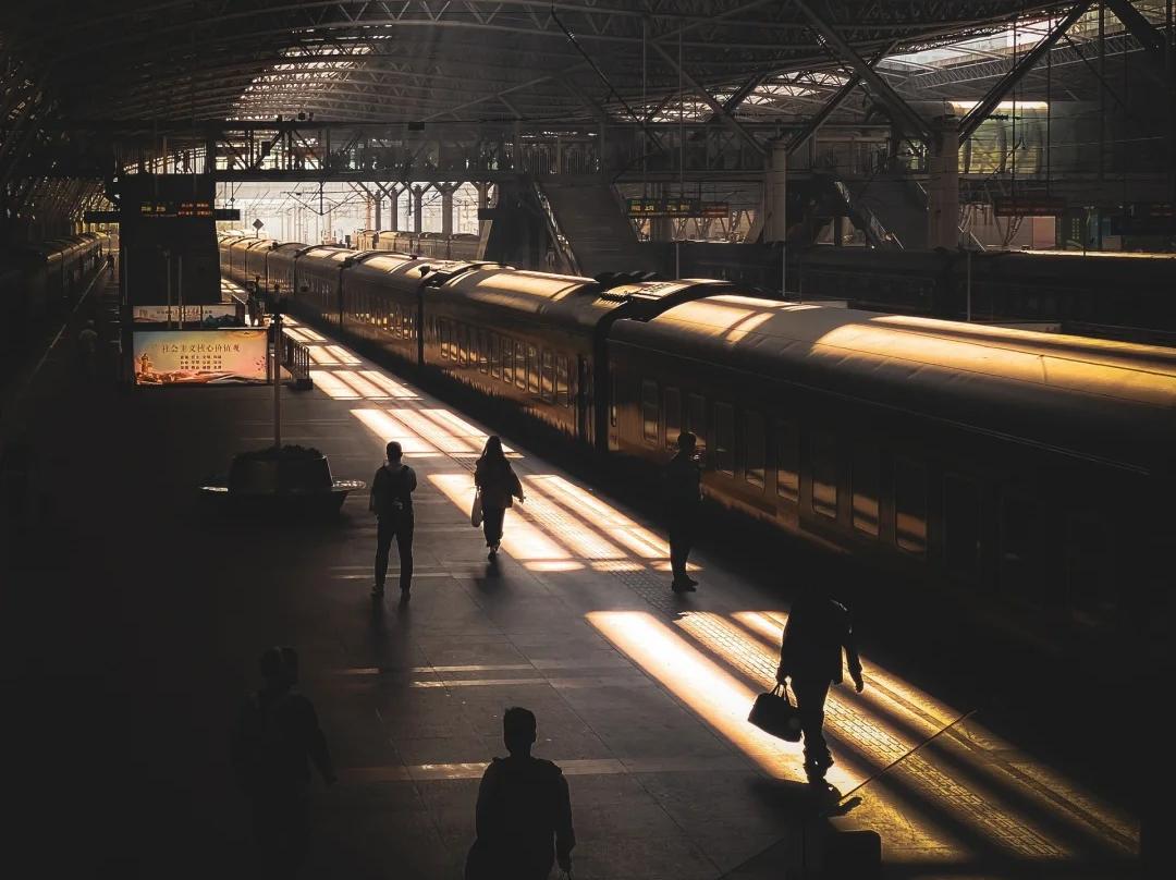 Vintage Passenger Train and Travellers Silhouettes in Sunlit Grand Railway Station Hall Vintage Passenger Train and Travellers Silhouettes in Sunlit Grand Railway Station Hall