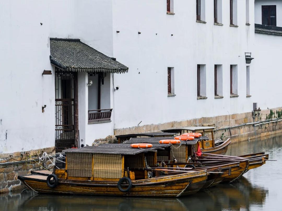 Wooden tour boats docked at Suzhou water town riverbank