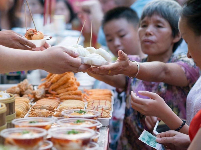 Traditional Chinese street food stall with customers buying snacks
